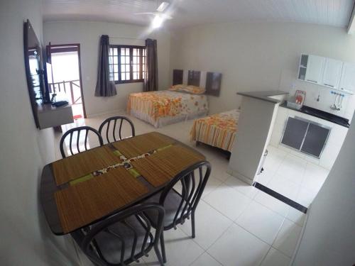 a room with a table and chairs and a kitchen at Suítes do Cid in Abraão