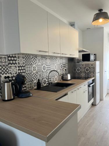 une cuisine avec des armoires blanches et un comptoir dans l'établissement MahéRius N 1, à Gerbéviller