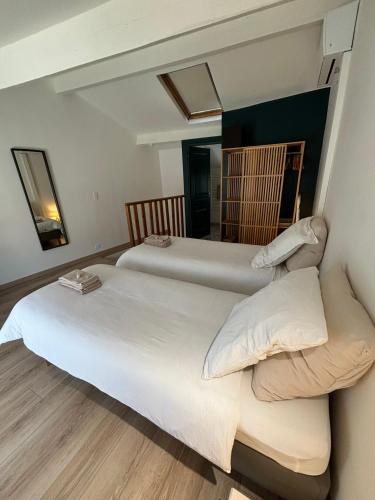 deux lits dans une chambre avec un miroir dans l'établissement Beausoleil, à Avignon