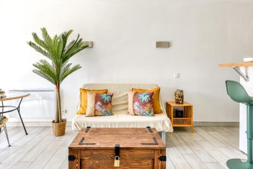- un salon avec un canapé et un palmier dans l'établissement Locapdagde Jungle Suite Hyper Centre Port Wifi Clim Ménage incl, au Cap d'Agde
