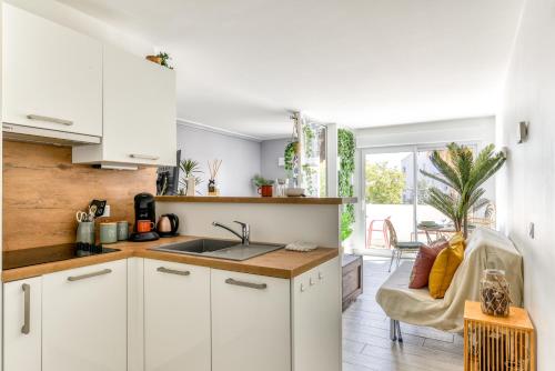 une cuisine avec des armoires blanches et un évier dans l'établissement Locapdagde Jungle Suite Hyper Centre Port Wifi Clim Ménage incl, au Cap d'Agde