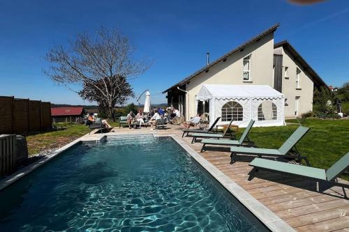 a swimming pool with chairs and a table and a building at LA MAISON DES VOSGES Nature & Pool in Senones