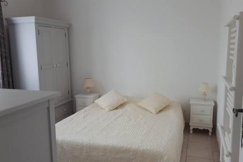 VelleronにあるNice flat with jacuzzi and gardenの白いベッドルーム(ベッド1台、ナイトスタンド2台付)