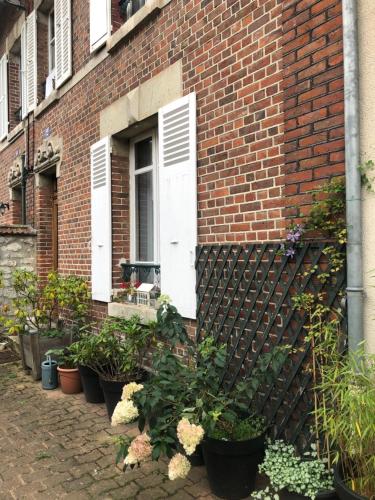 un bâtiment en briques avec une bande de plantes en pot dans l'établissement Chez Sophie, à Crépy-en-Valois