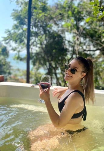 a woman in the water holding a glass of wine at Double Deck - Linda vista com Jacuzzi in Palhoça