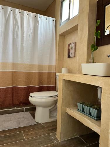 a bathroom with a toilet and a shower curtain at Villa Lulu in Chicxulub
