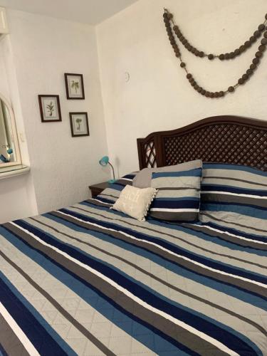 a bedroom with a bed with blue and white stripes at Villa Lulu in Chicxulub