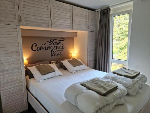 a bedroom with a white bed with a sign on the wall at Apartment with beautiful views near Durbuy in Durbuy