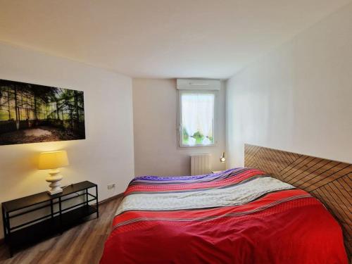 une chambre avec un grand lit avec une couverture rouge dans l'établissement Votre cocon avec baignoire et Wifi à 15 min à pied du centre d'Amiens, à Amiens