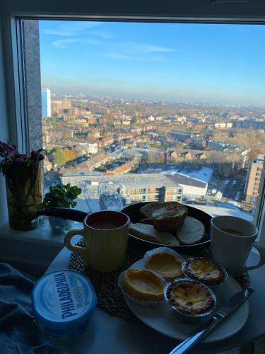 a breakfast table with a view of a city from a window at Cozy Flat with Stunning Views in London