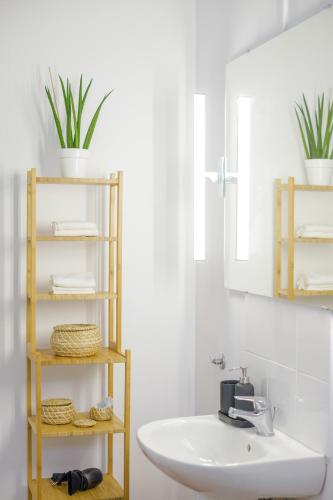 a bathroom with a sink and a shelf with plants at Alethea's Sea View Apartment in Kalamaki