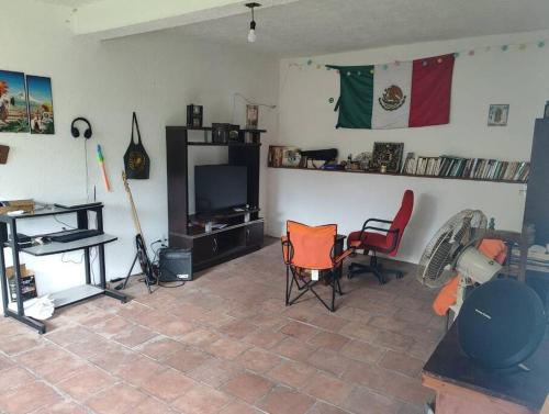 a living room with two chairs and a television at Casa de la Rosa in Malinalco
