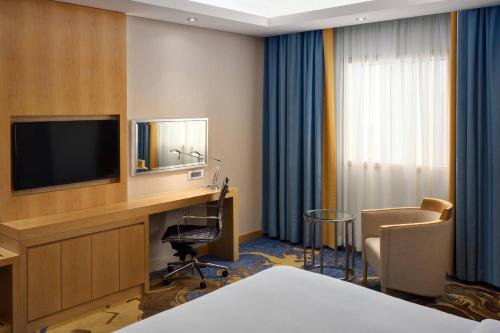 a hotel room with a television and a desk with a chair at Sheraton Makkah Jabal Al Kaaba Hotel in Makkah
