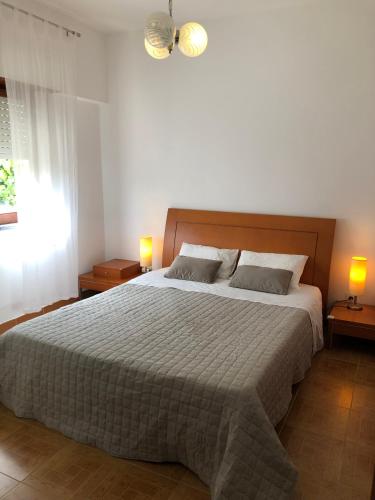 a bedroom with a large bed with two lamps at Casa da Bisa in Sagres