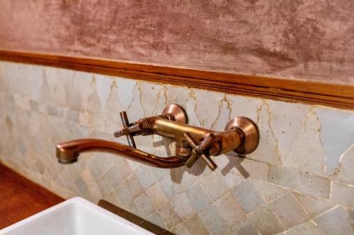 a bronze water faucet on a wall next to a sink at Dar Attajalli in Fès