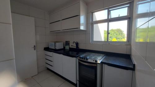 una cucina bianca con lavandino e finestra di Leonis, Apto 32 a Curitiba