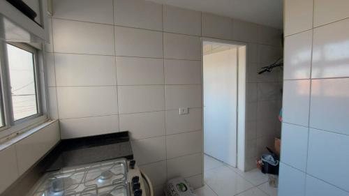 un bagno piastrellato con lavatrice e finestra di Leonis, Apto 32 a Curitiba