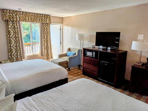 a hotel room with two beds and a flat screen tv at Pocono Inn & Banquet - Stroudsburg in Delaware Water Gap
