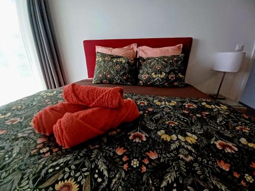 a bed with two red pillows on top of it at Logement Cosy avec Piscine et Vue Tahiti Punaauia in Punaauia