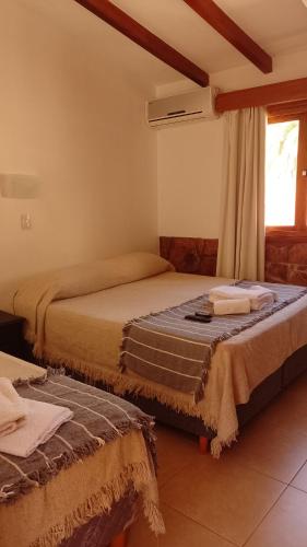 two beds in a room with a window at Ribera Sur Hotel - Los Algarrobos - Tanti in Tanti