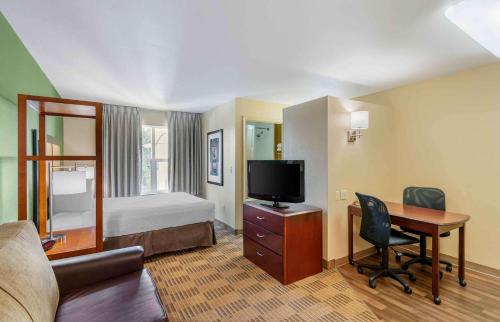 a hotel room with a bed and a desk with a television at Extended Stay America Suites - Portland - Hillsboro in Hillsboro