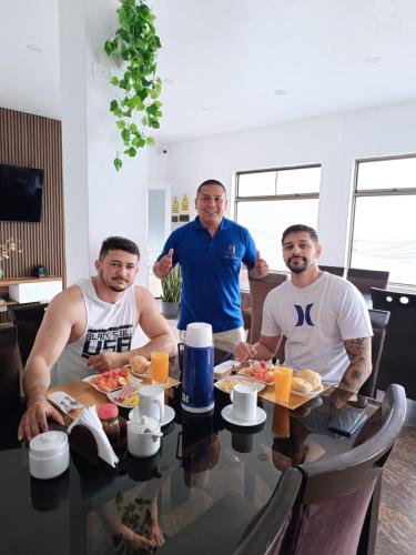a group of three men sitting at a table with food at Hotel San Martín in San Juan de Marcona