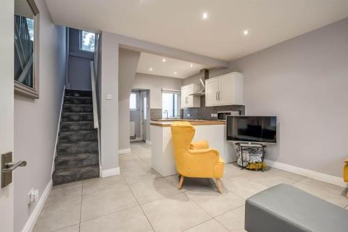 a living room with a yellow chair and a kitchen at Belfast City Home in Belfast