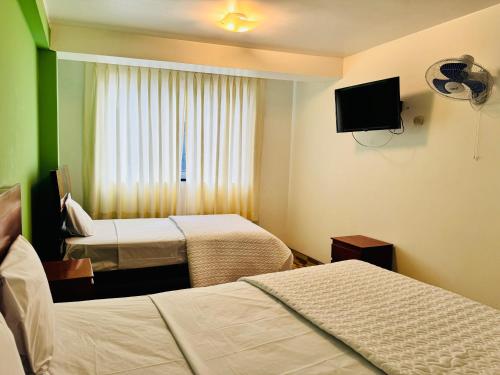 ein Hotelzimmer mit zwei Betten und einem Flachbildfernseher in der Unterkunft Hotel Puerto Bayovar II in Mala