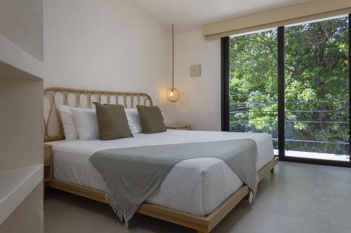 a bedroom with a large bed and a large window at Ikana Puerto Aventuras Golf Getaway in Puerto Aventuras