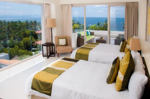 two beds in a room with a view of the ocean at Marival Distinct Luxury Residences & World Spa All Inclusive in Nuevo Vallarta