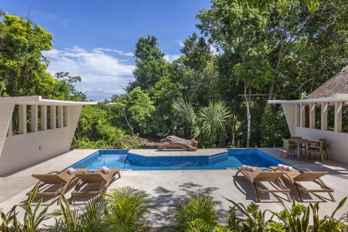 a patio with chairs and a swimming pool at Ikana Puerto Aventuras Golf Getaway in Puerto Aventuras