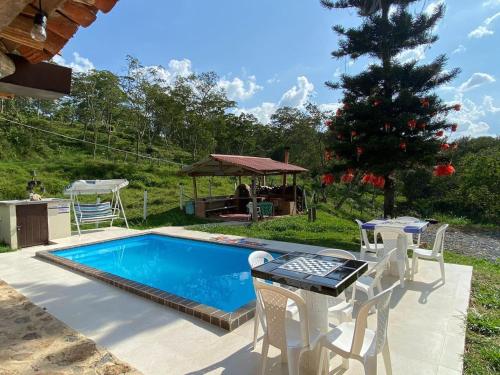 una piscina con sillas, una mesa y un cenador en Alojamiento Rural Granja La Ilusión, en Las Esquinas
