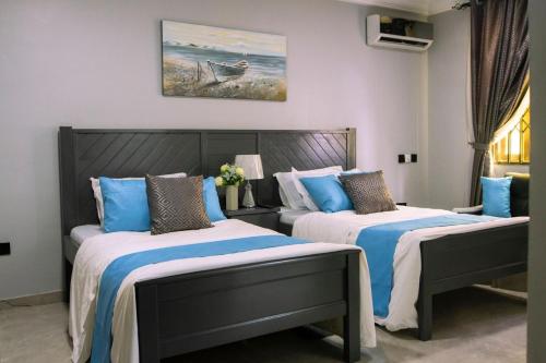 a bedroom with two beds with blue and white sheets at KCS Guesthouse in Otinshi