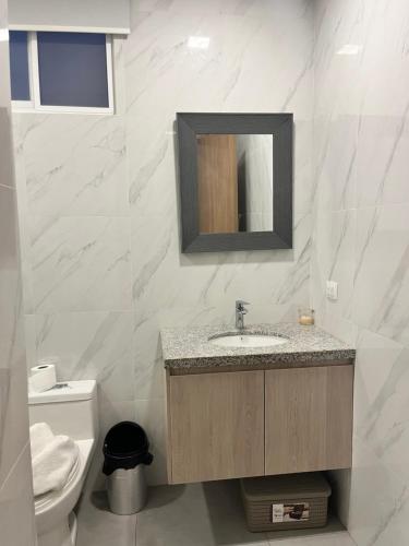 a bathroom with a sink and a toilet and a mirror at Al-Mar Departamento Playero in Salinas