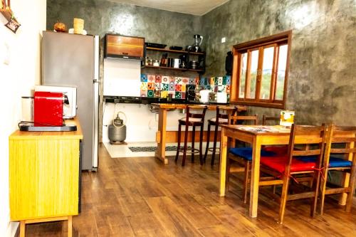 a kitchen with a table and a refrigerator at Chalé Serra dos tucanos in Gonçalves