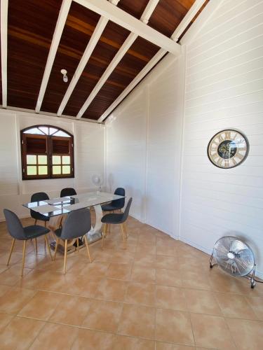 a dining room with a table and chairs and a clock at Villa Créole vue exceptionnelle Perle des Hauteurs in Le Carbet
