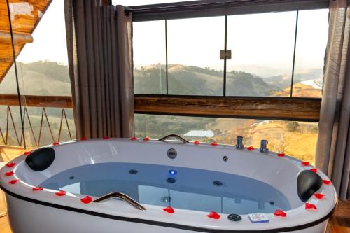a bath tub in a room with a large window at Chalé Serra dos tucanos in Gonçalves