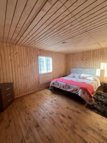 a bed in a room with a wooden ceiling at Quilquico Lodge in Castro
