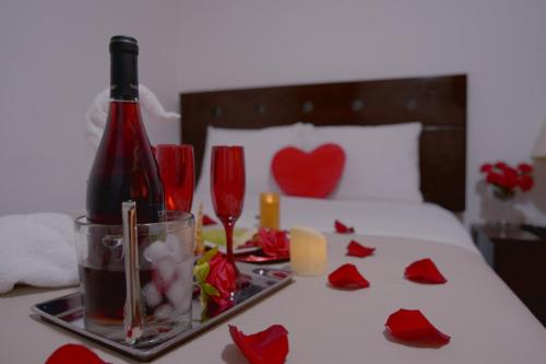 a bottle of wine and red roses on a bed at Hotel San Martín in San Juan de Marcona
