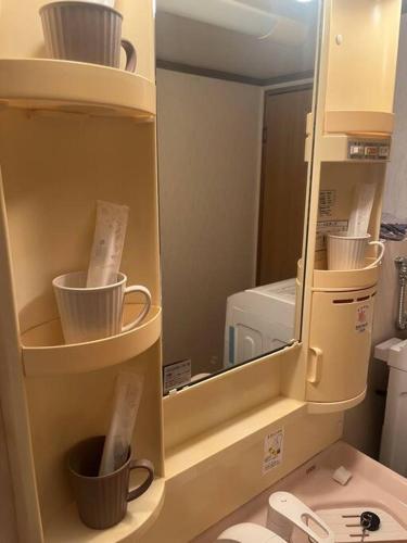 a cabinet with cups and a microwave in a bathroom at ゲストハウス町家はま in Izumi-Sano