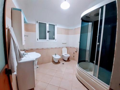 a bathroom with a toilet and a sink and a shower at Villas for rent Elena feeling home in Durrës