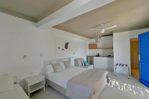 a white bedroom with a bed and a kitchen at Eleni On The Beach in Katapola