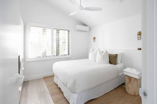 Un dormitorio blanco con una cama blanca y una ventana. en Otto Descola - Views, walk to Hastings St & beach, en Noosa Heads