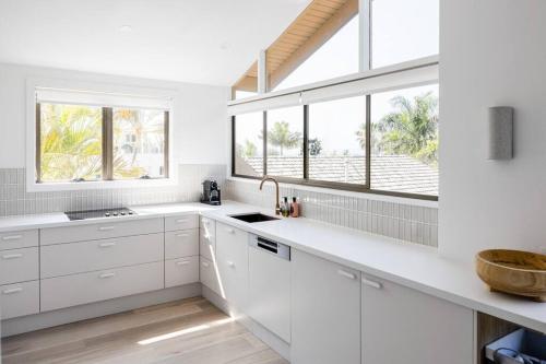una cocina blanca con armarios blancos y ventanas en Otto Descola - Views, walk to Hastings St & beach, en Noosa Heads
