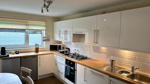 a kitchen with white cabinets and a stove top oven at The Red Door, Two-Bedrooms Apartment in Edinburgh