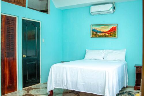 a blue bedroom with a bed with a white blanket at Veronica Villa 68 in Lucea