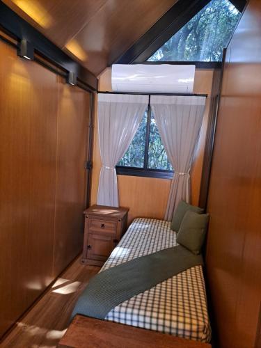 a small room with a bed and a window at Cabana do Mato Waldhütte in Treze Tílias