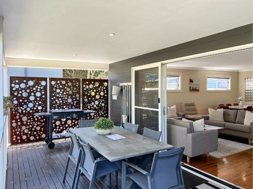 a living room with a table and chairs and a couch at 3-Bed Coastal Haven with Alfresco Dining & BBQ in Marks Point