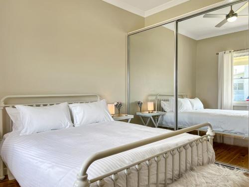 a bedroom with two beds and a large mirror at 3-Bed Coastal Haven with Alfresco Dining & BBQ in Marks Point