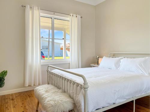 a bedroom with a white bed and a window at 3-Bed Coastal Haven with Alfresco Dining & BBQ in Marks Point